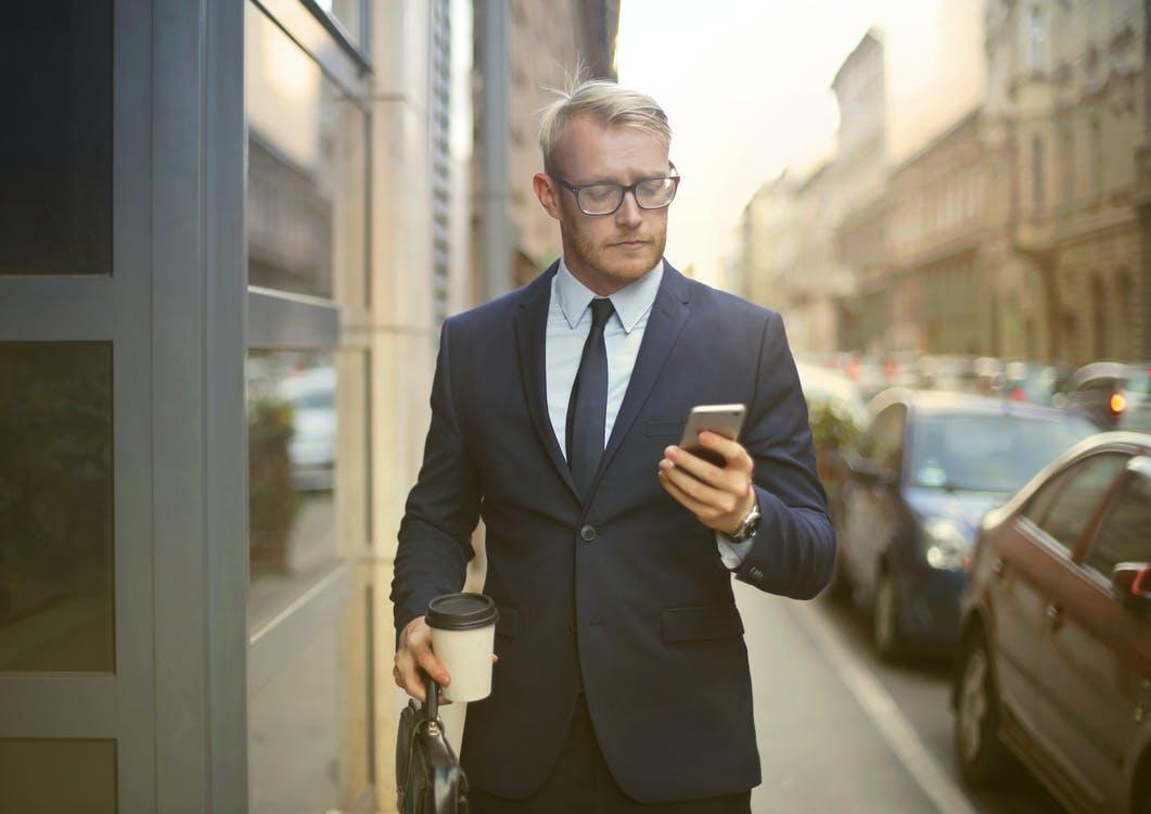 A business executive using his phone while walking toward his car.