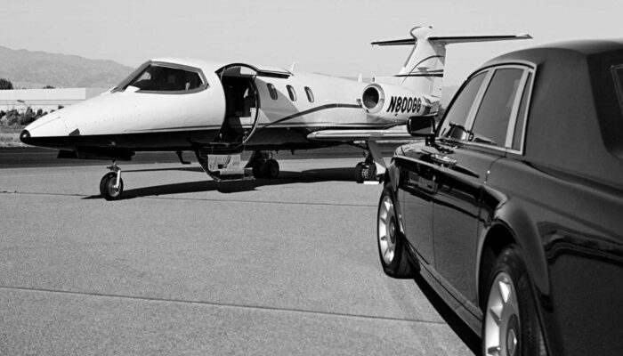 A limo arriving at the airport near parked plane.