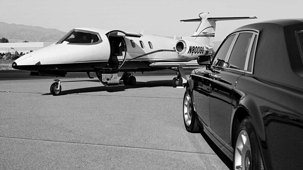 A limo arriving at the airport near parked plane.