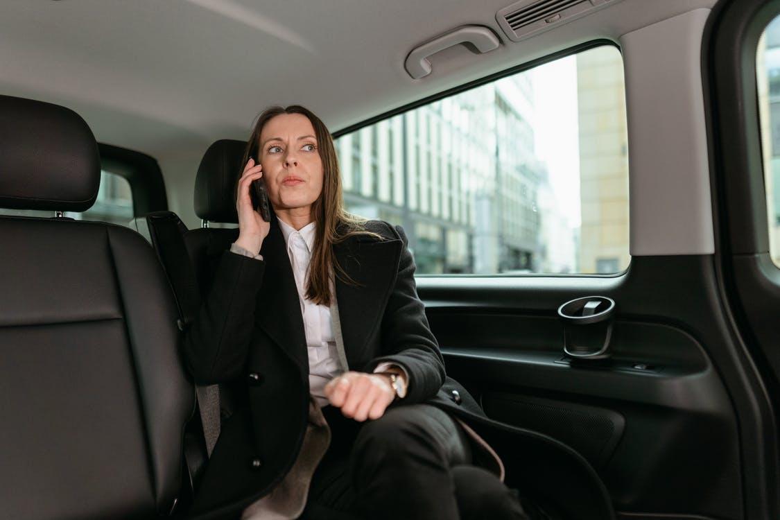 A businesswoman on call inside a luxury car