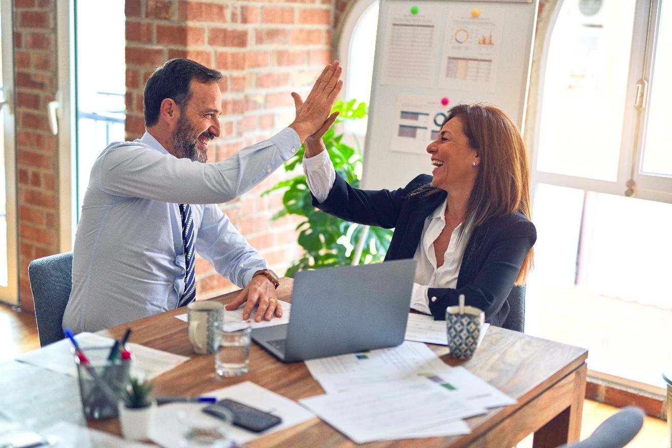 A man and woman high-fiving in an office