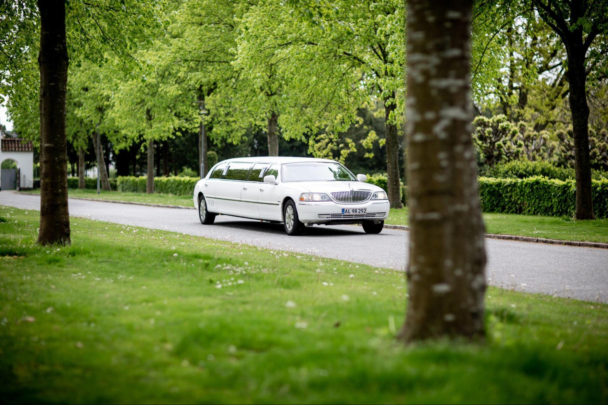 A white limo service car on a road